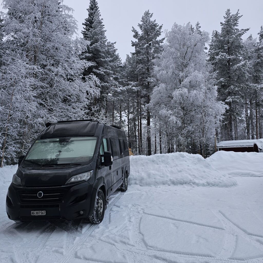 schwarzer Kastenwagen mit winterlicher weisser Umgebung, Frost an den Scheiben, Schneestrasse